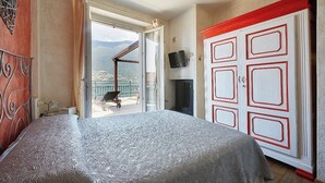 Un dormitorio con cama, televisor, armario y balcón con vistas.
