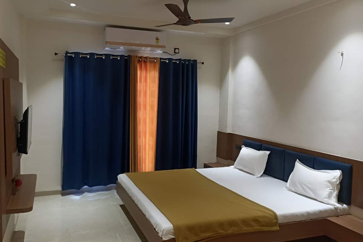 Una habitación de hotel con una cama, un ventilador de techo y cortinas.