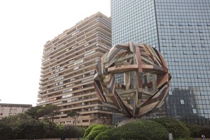 Un edificio moderno con una escultura esférica singular al frente.