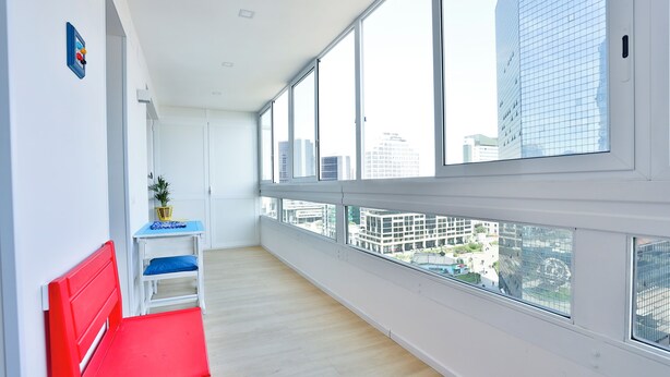 A room with a red bench, a small table with a blue cushion, and large windows offering a city view. - Naples Stay Inn - close to metro & all connections (Napoli)