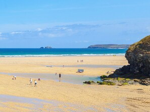 A beach with clear skies, calm waters, and rocky cliffs. - The Cottage (St Ives)