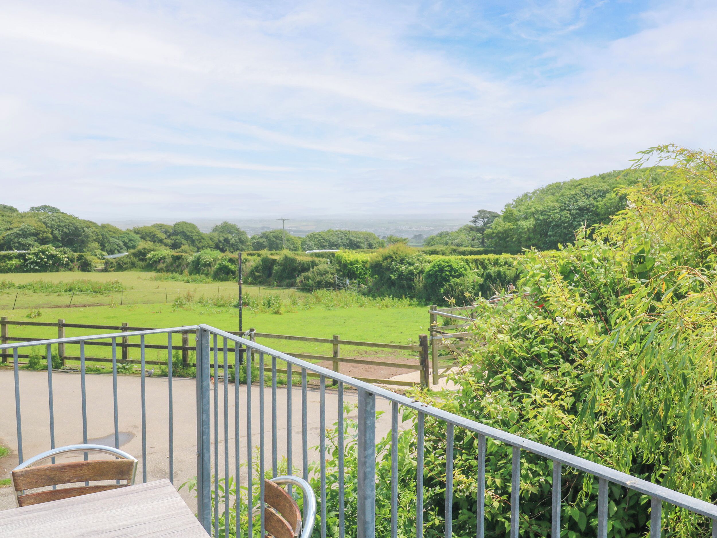 Un balcon donnant sur un champ verdoyant et sur des collines lointaines.