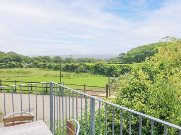 A balcony with a view of a green field and distant hills. - The Cottage (St Ives)