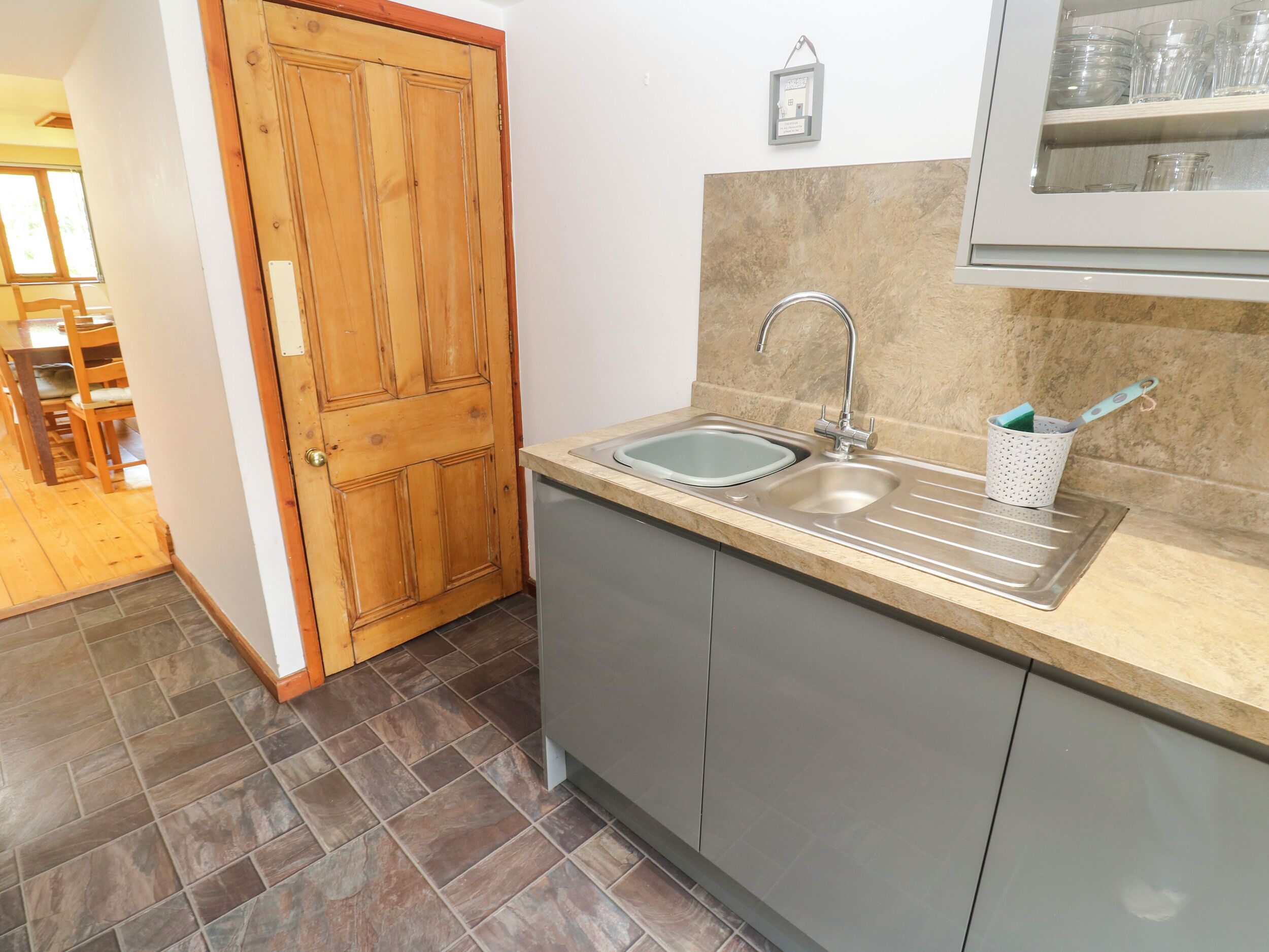 A kitchen with a wooden door, a sink, and a cabinet.
