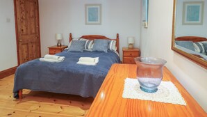 Une chambre à coucher avec un lit en bois, deux tables de chevet avec des lampes, une armoire en bois et un grand miroir au mur.