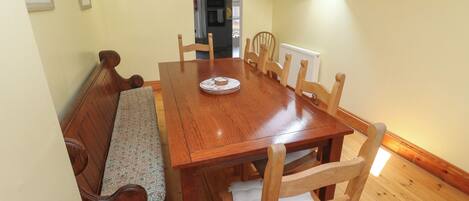 A dining area with a wooden table, benches, and chairs.