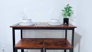 A dining table with white plates and bowls, a fork, spoon, and a glass. There is a potted plant on the table.
