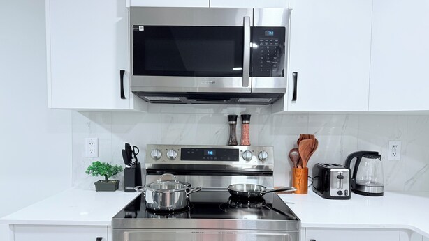 A modern kitchen with stainless steel appliances, including a microwave, oven, and stovetop.