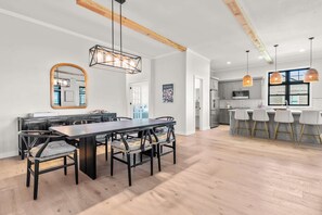 A modern kitchen with a bar area, wooden beams, and a dining area with a large table and chairs.