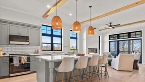 Una cocina moderna con una isla grande, luces colgantes y vistas al exterior.