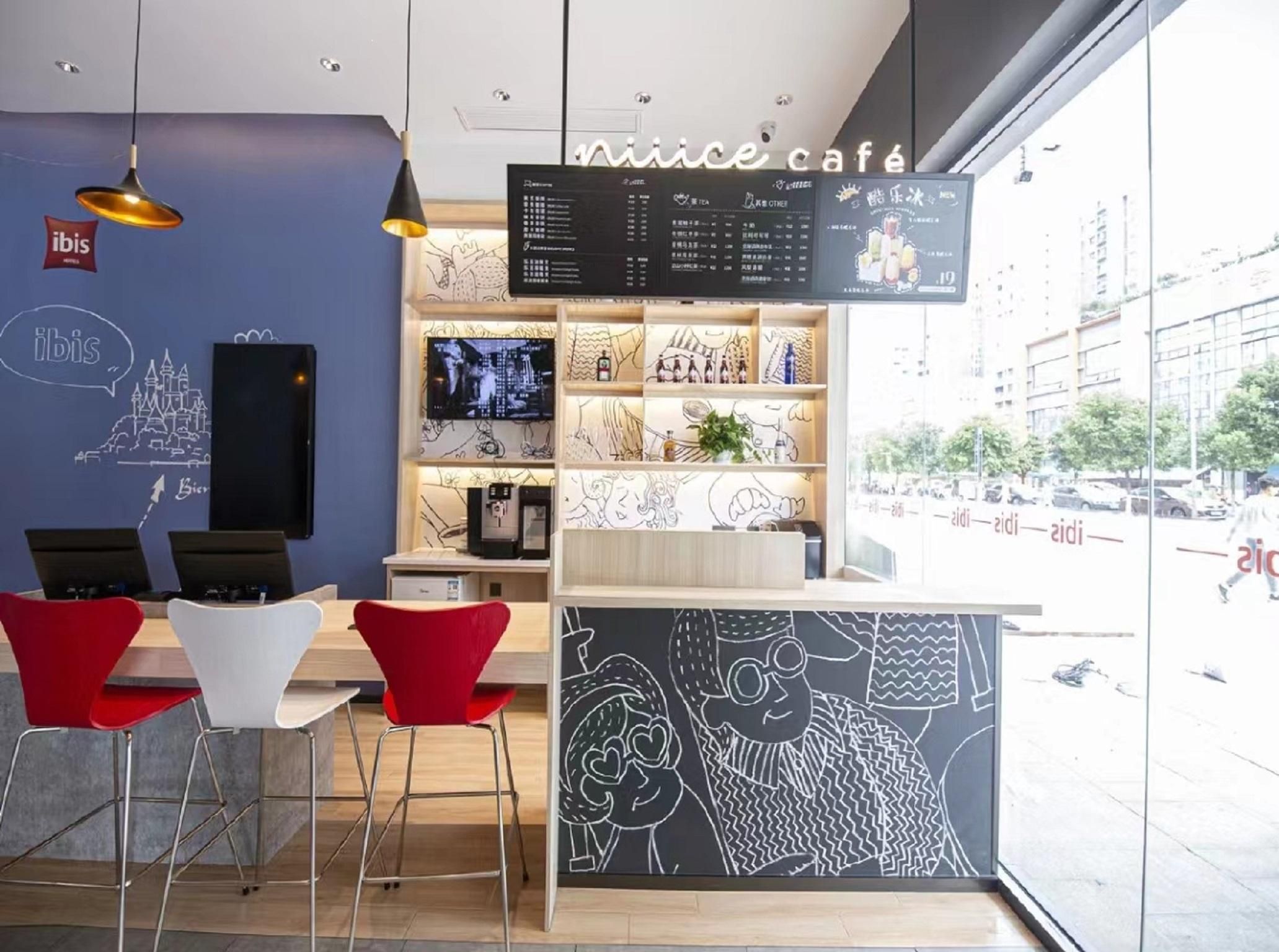 A modern cafe interior with a menu board, seating area, and a view of the street outside.
