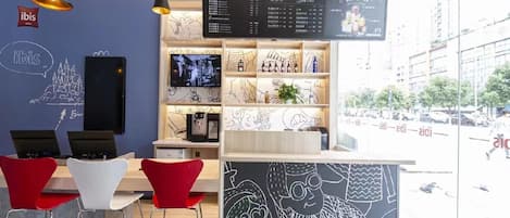 A modern cafe interior with a menu board, seating area, and a view of the street outside.