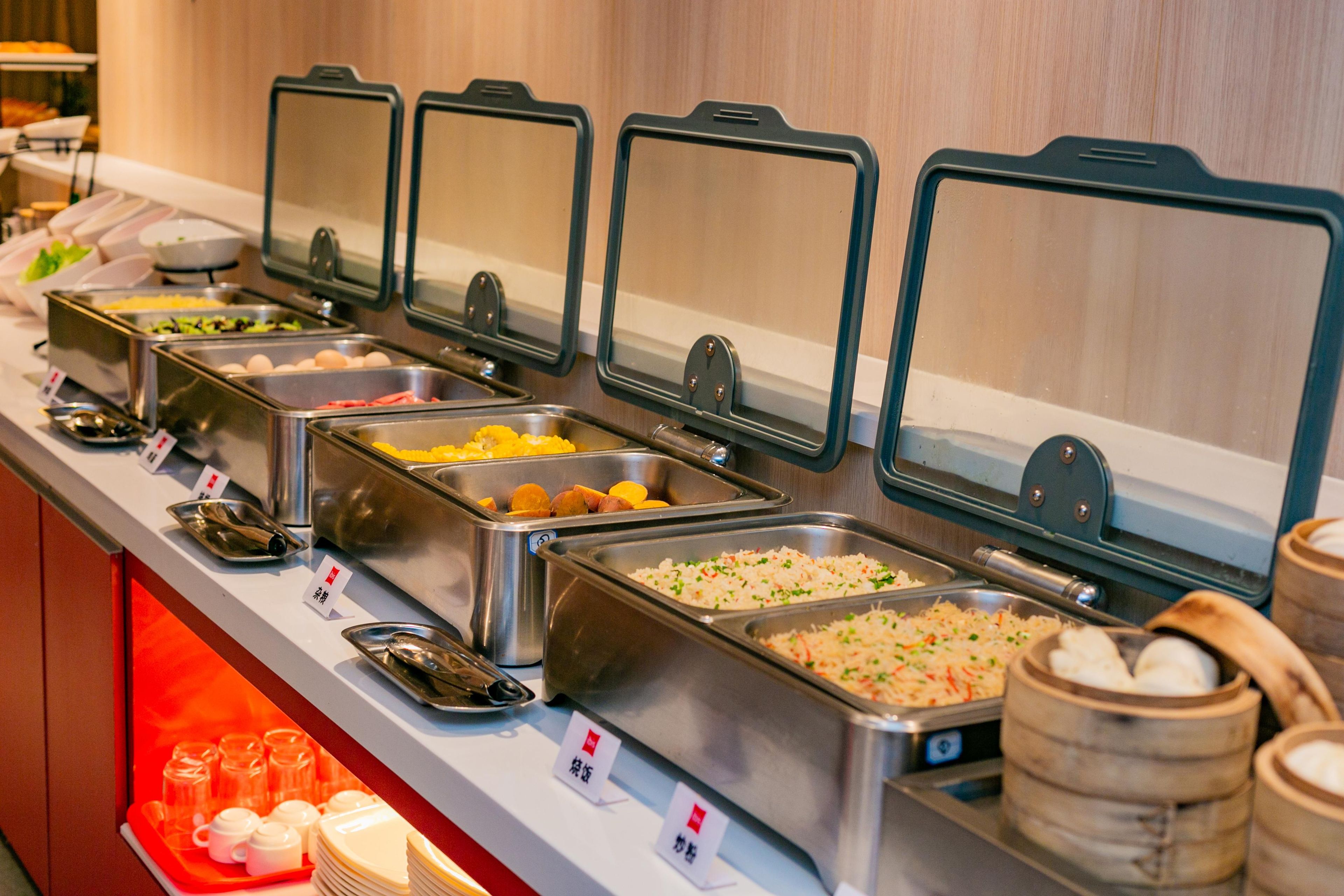 A buffet with various food items and containers, including trays and bowls.
