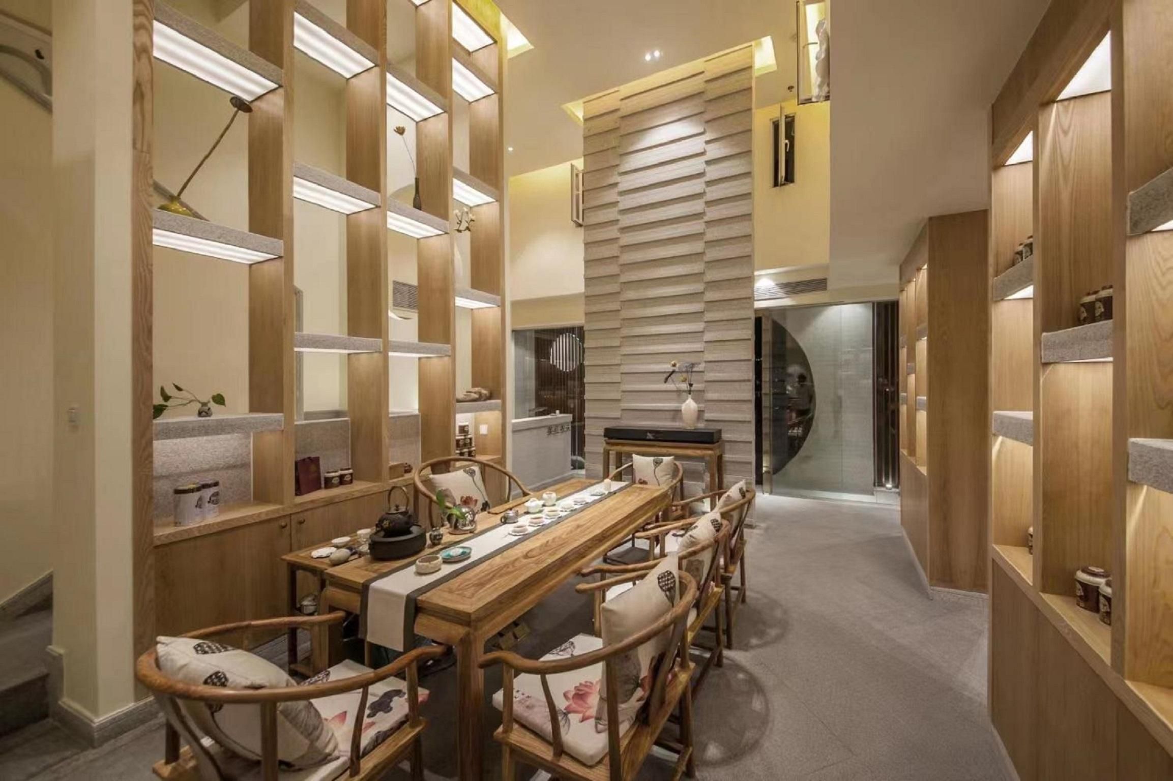 Uma sala de jantar moderna com uma longa mesa de madeira e cadeiras, cercada por divisórias e prateleiras de madeira com diversos objetos.