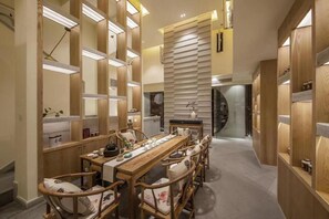 A modern dining area with a long wooden table and chairs, surrounded by wooden partitions and shelves with various items. - Ibis Chengdu Gaoxin Tianfu Software Park Hotel (Chengdu)