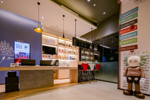 Un café doté d’un bar, d’un menu numérique affiché sur écran et d’une grande statue représentant sa mascotte.