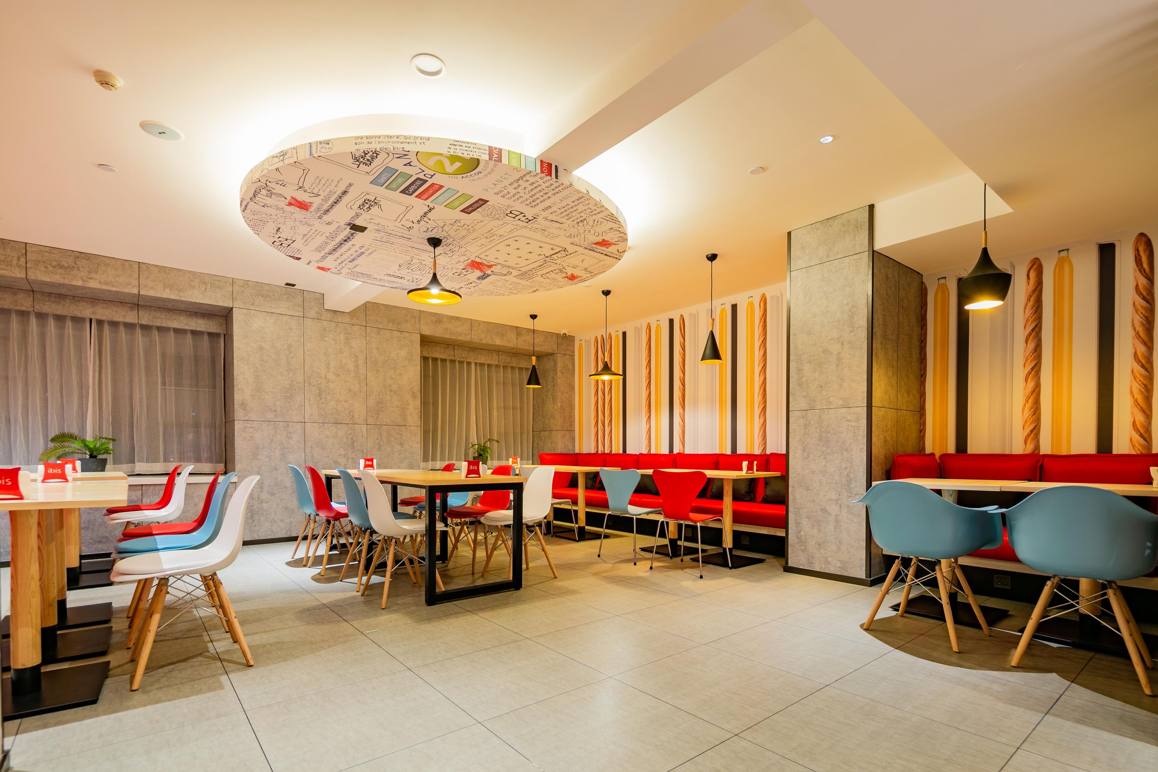 Un restaurante moderno con mesas redondas, sillas coloridas y un diseño de techo único.