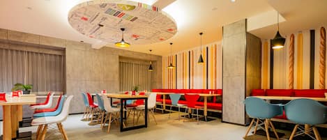 A modern restaurant with round tables, colorful chairs, and a unique ceiling design.