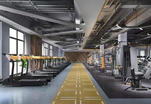 Une salle de sport moderne, avec des tapis de course alignés d’un côté et des appareils de musculation de l’autre.
