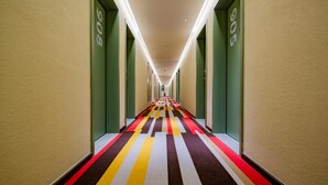 A hotel hallway with a colorful carpet, green walls, and a series of doors on one side. - Ibis Chengdu Gaoxin Tianfu Software Park Hotel (Chengdu)