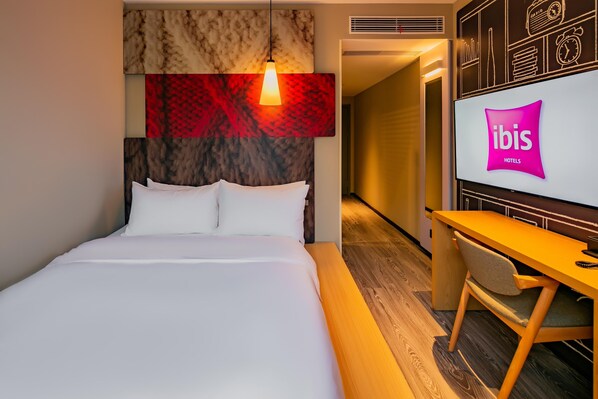 A hotel room with a bed, a desk, and a TV displaying the ibis logo. - Ibis Chengdu Gaoxin Tianfu Software Park Hotel (Chengdu)