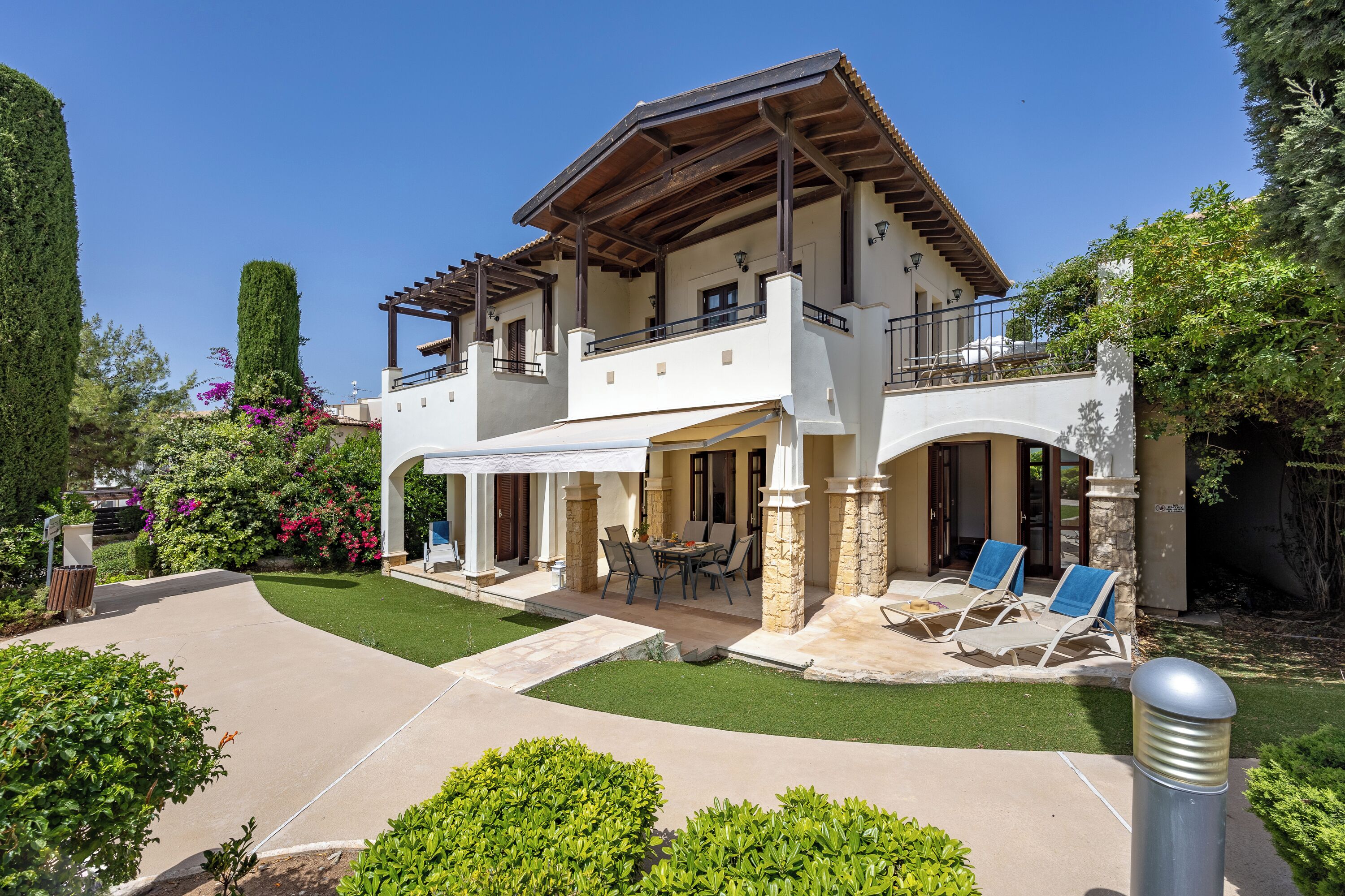 A two-story house with a patio, outdoor seating, and a well-maintained garden.