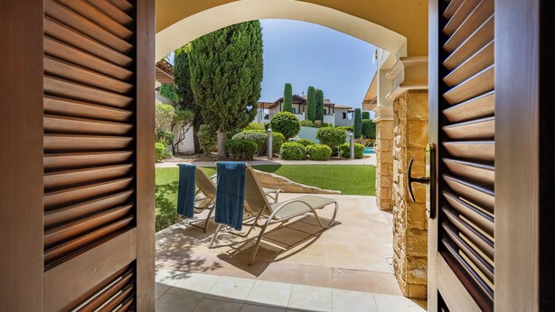 A patio area with a stone floor, a metal chair, and a blue towel on the chair. - Da02 Adjacent to Aphrodite Hills Pool View (Kouklia)
