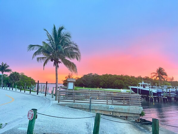 A waterfront promenade with a stop sign, a wooden bench, and a sign indicating no trespassing.