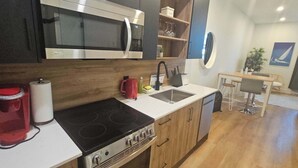 A compact kitchen with a microwave, stove, sink, and wooden cabinets.