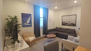 A living room with a sofa, chairs, a coffee table, a TV, and artwork on the walls.