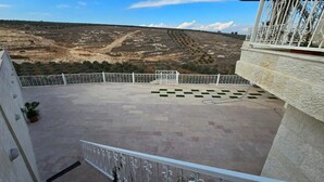 A balcony with a view of a barren landscape, a patterned floor, and a metal railing. - Charming 3-bedroom scenic villa with a pool, WiFi in the lovely north (يبلا (إربد))