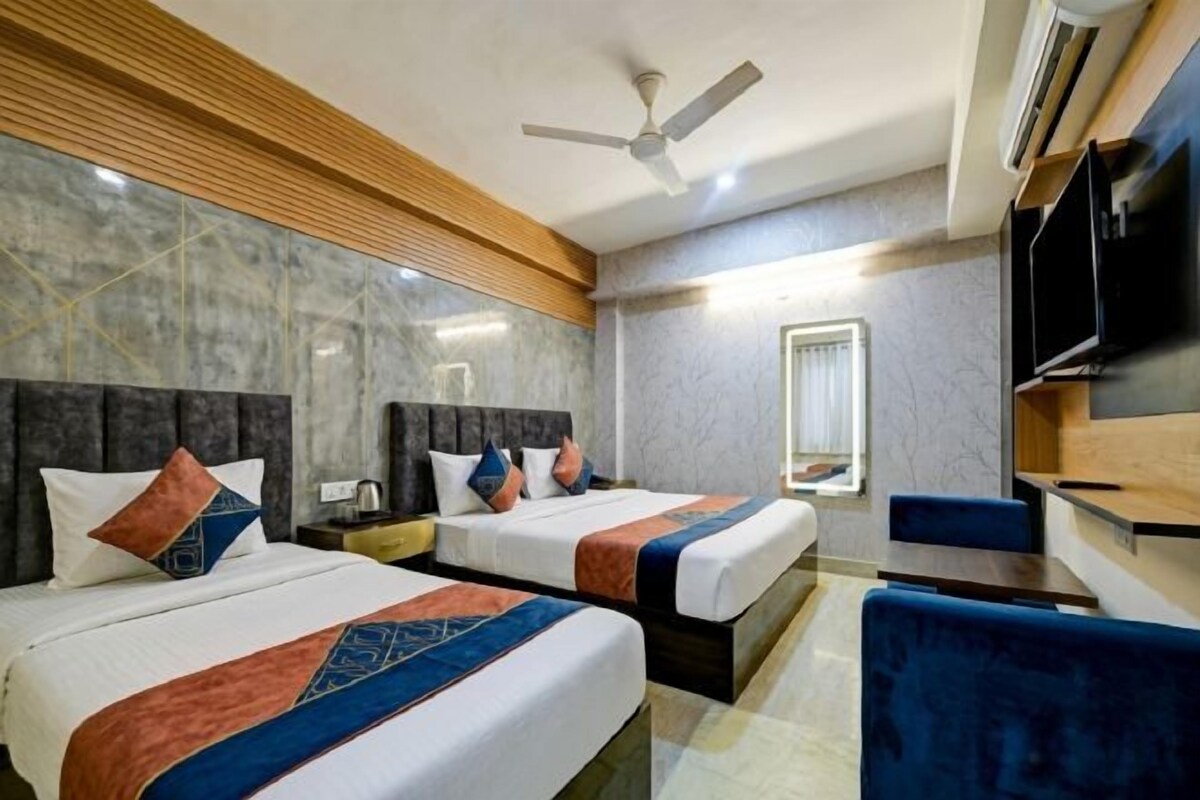 A hotel room with two beds, a flat-screen TV, a ceiling fan, and a wooden panel wall.