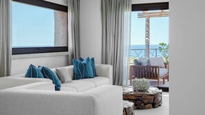 A modern living room with a sectional sofa, a wooden coffee table, and a view of the sea through large windows. - La Tiara di Cervo  (Arzachena)