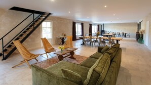 A spacious living area with a staircase, seating, and a dining area.