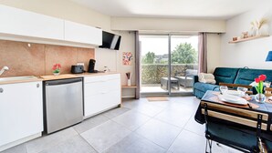Eine moderne Küche mit Geschirrspüler, ein Essbereich mit Tisch für zwei Personen und eine Glastür, die auf einen Balkon führt.