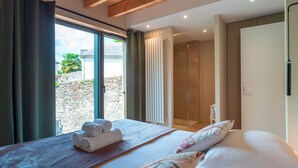 Un dormitorio moderno con una cama grande, techo de madera y vistas al exterior, además de un área de ducha.