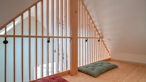 Un dormitorio tipo loft con techo inclinado, vigas de madera y vistas al exterior.