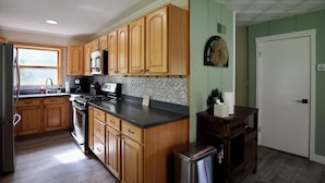 A kitchen with wooden cabinets, a black countertop, a stainless steel refrigerator, and a microwave. - Good Decision on the Mo- Cascade, MT (Cascade)