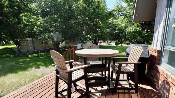 A wooden deck with a round table and four chairs, surrounded by trees and a brick wall. - Good Decision on the Mo- Cascade, MT (Cascade)