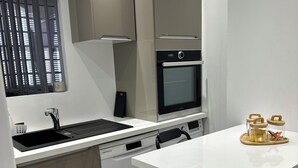 A compact kitchen with a dishwasher, oven, and a small dining area with a table and chairs. - The Charm of Anduze (Anduze)