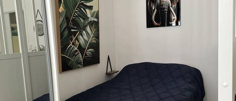 A bedroom with a bed, a large mirror, and two wall-mounted artworks.