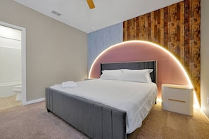 Un dormitorio moderno con una cama grande, una mesita de noche y un elemento decorativo en una pared curva.