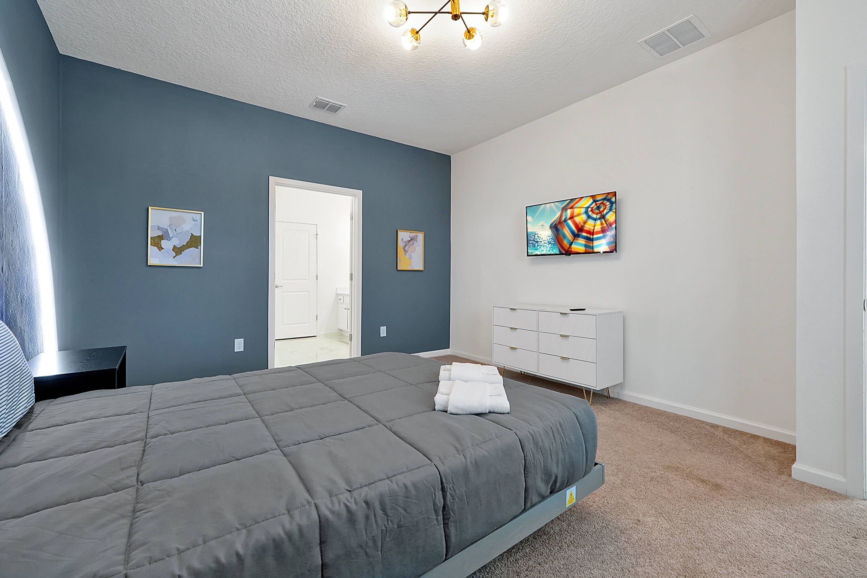 A bedroom with a large bed, a dresser, and a painting on the wall.