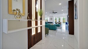 Eine moderne Hotelhalle mit Marmorboden, einer Rezeption, einer Sitzecke mit Türkis-Farbenen Sofas und einem großen Spiegel.