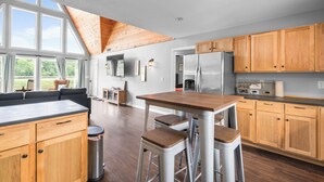 A modern kitchen with wooden cabinets, a stainless steel refrigerator, and a large window overlooking a garden. - Spacious 4BR Cabin in Doniphan – Perfect for Family Getaways (Doniphan)