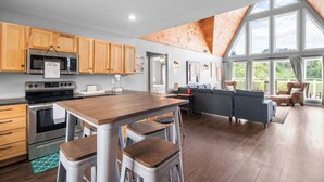 A modern kitchen with wooden cabinets, a stainless steel oven, and a large island with stools. - Spacious 4BR Cabin in Doniphan – Perfect for Family Getaways (Doniphan)