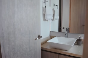 Ein modernes Badezimmer mit einem großen weißen Waschbecken, einem Spiegel und einem Handtuchhalter.