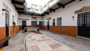 A courtyard with a tiled floor, potted plants, and a wooden bench.