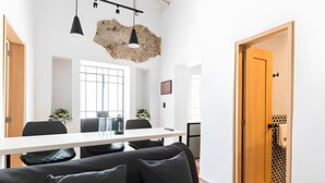 A modern meeting room with a white table, black chairs, and a large window.