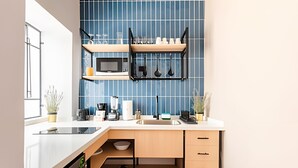 A modern kitchen with a blue tiled backsplash, a microwave, a sink, and a countertop with various appliances and utensils.